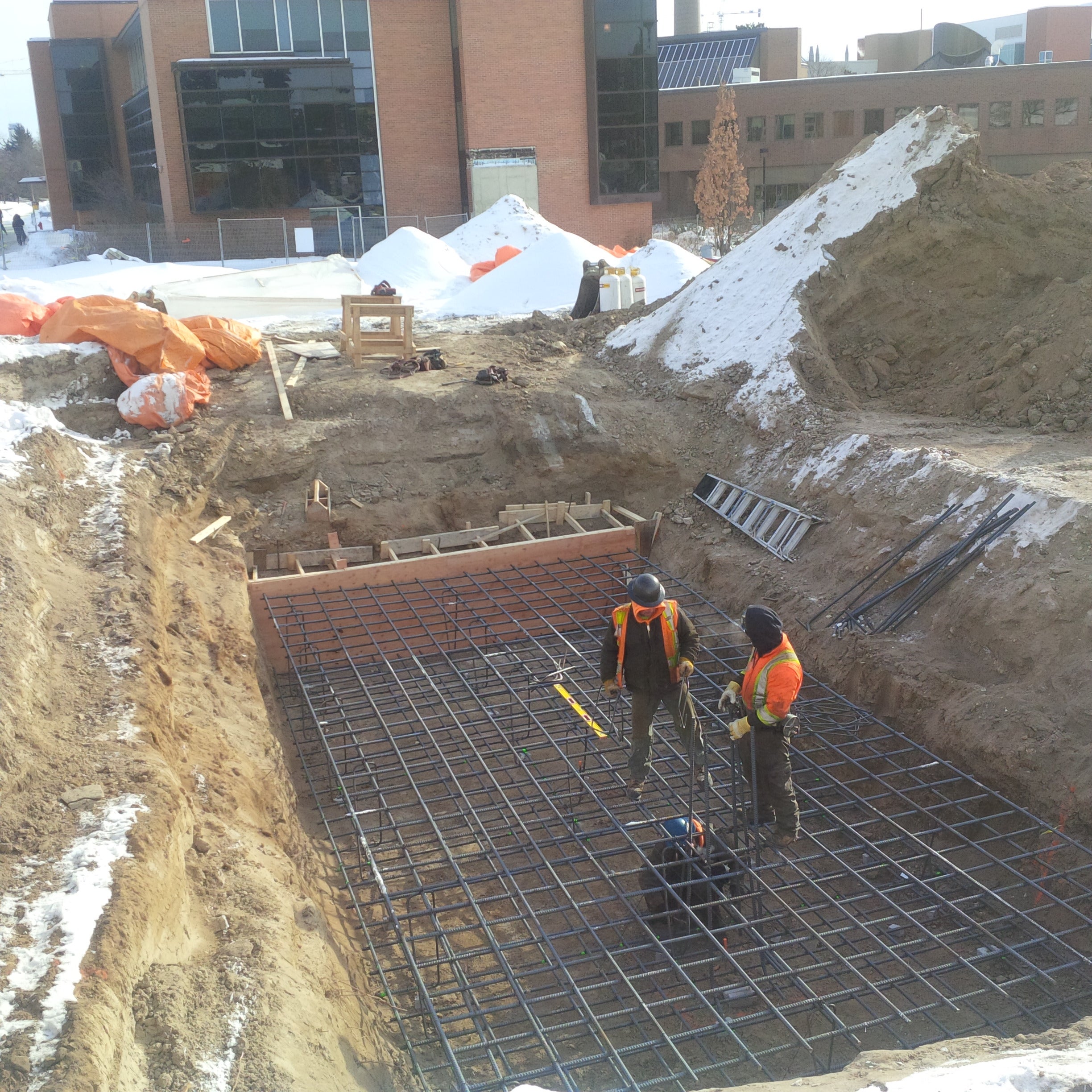 Construction workers placing rebar for north footing of expansion building.