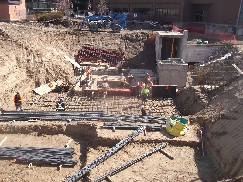 Construction workers installing rebar and concrete molds from basement footings.