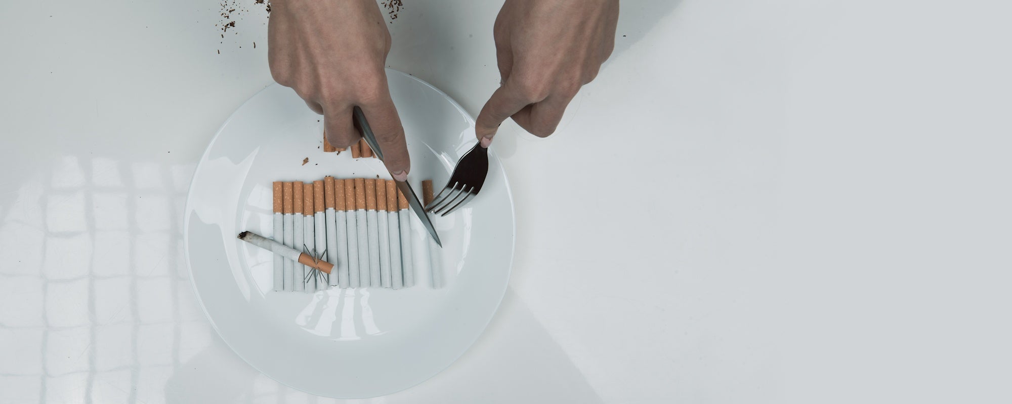 Person cutting cigarettes on a plate