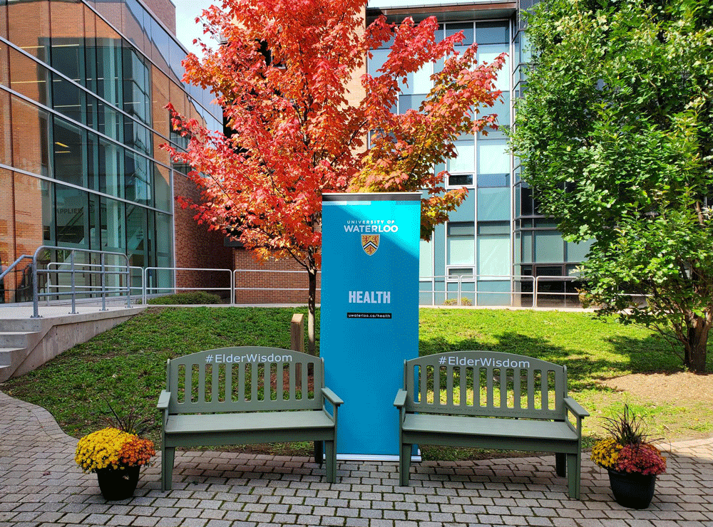 Two elder wisdom benches in BMH courtyard with Health banner between them.