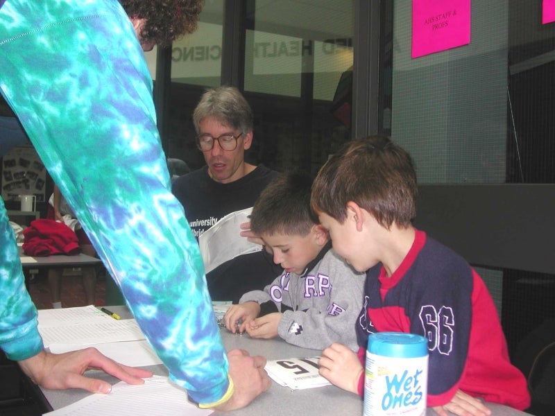 A participant signing up for the race while two boys and a man working at the registrar's desk.