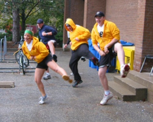 Three students in yellow hoodies and one in a blue sweater doing a dance move