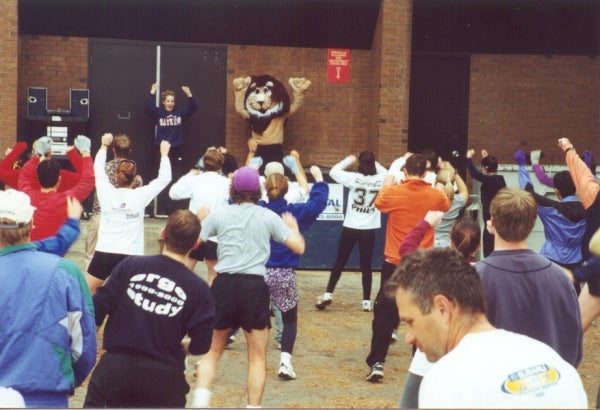 Participants stretching with an instructor in the front and the lion mascot