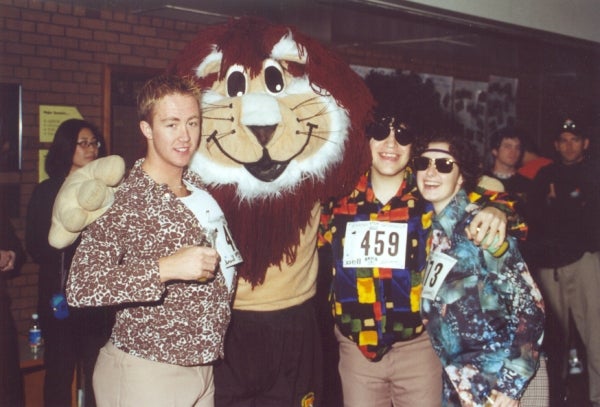 A lion mascot with three male participants 