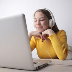 Student with headphones looking at a laptop.