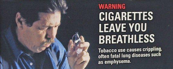 Smoking warning label showing a middle aged man holding an oxygen respirator while coughing
