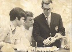 sepia image of professor showing anatomy models to students