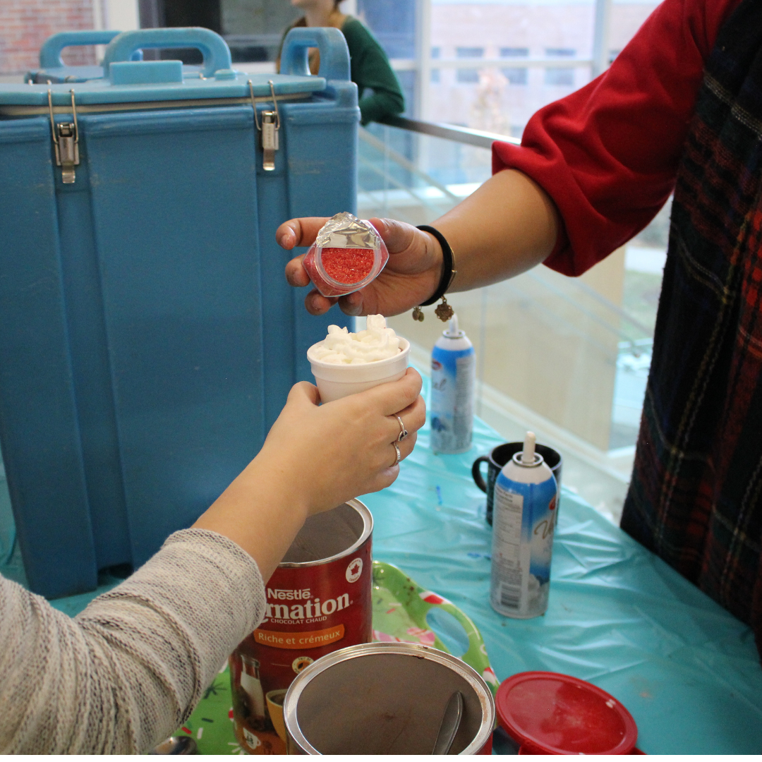 Hot chocolate with whipped cream and sprinkles being poured on top.