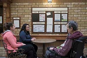 Kimberly Lopez sitting at table with older adults in long-term care home