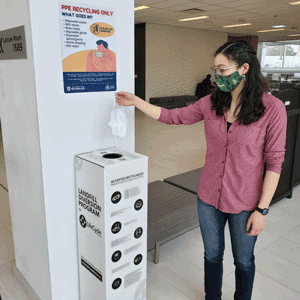 Person disposing of mask in a PPE recycling box.