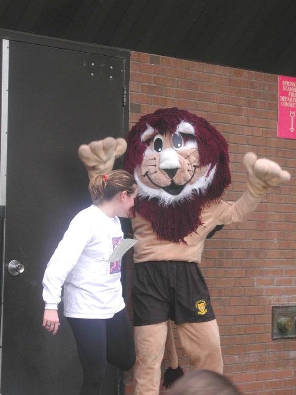 Female participant and a lion mascot stretching 