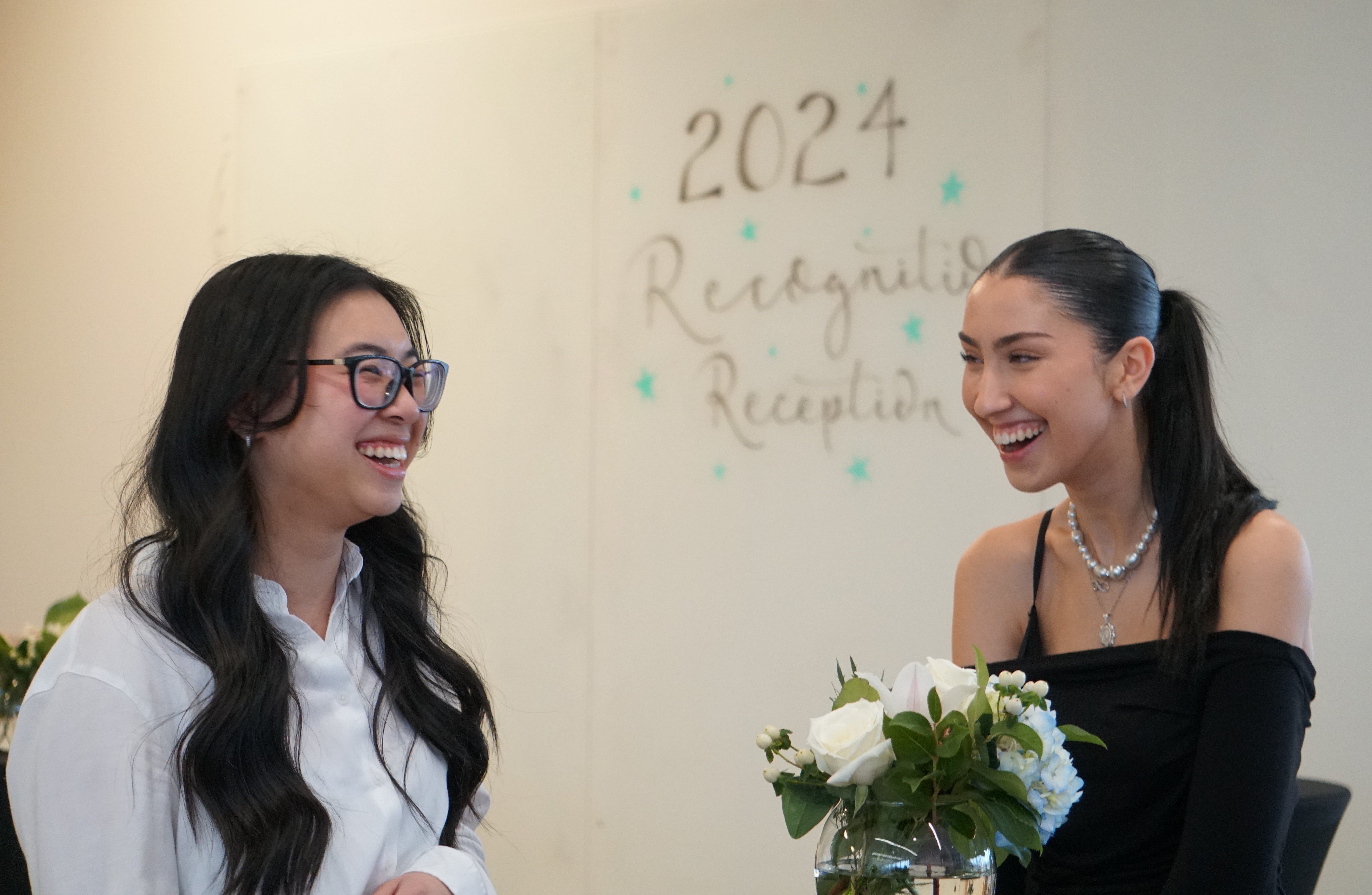 Two women laughing during conversation at the event.