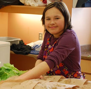 young girl at kitchen counter washing lettuce leaves
