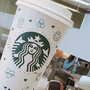 Starbucks cup with teal drawings drawn on the cup.
