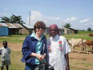 Susan Elliott in rural scene with Kenyan mother and livestock nearby