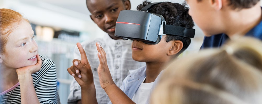 Child looking through VR goggles while others look on