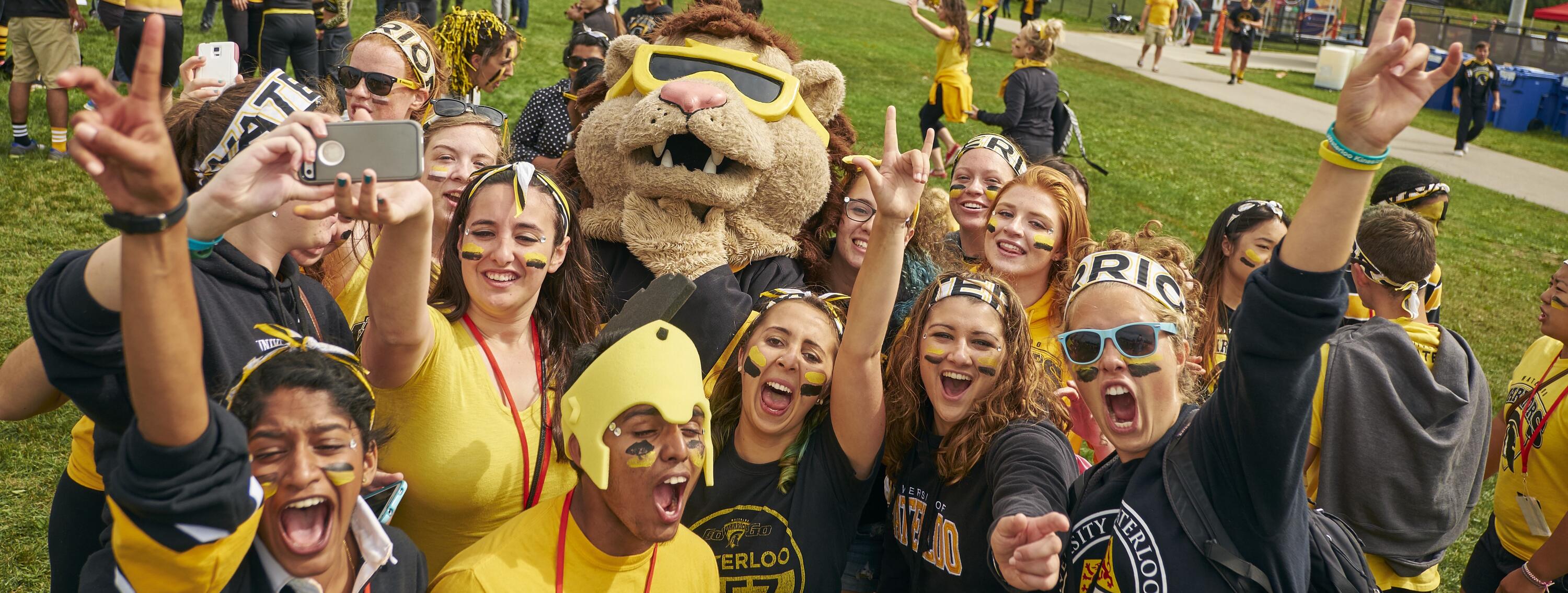 Students wearing black and gold clothing and makeup with university lion mascot
