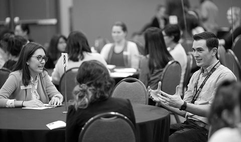 Staff and students conversing around a meeting table.