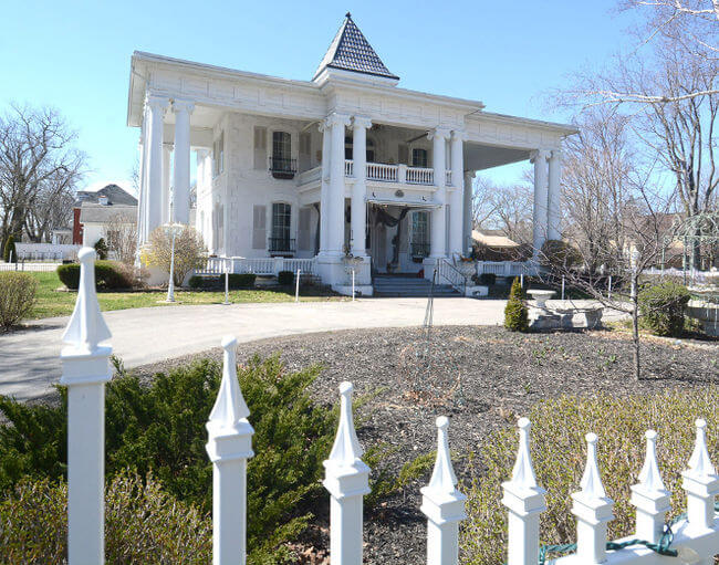 A front view of the Stratford White House building with a fence and garden in front