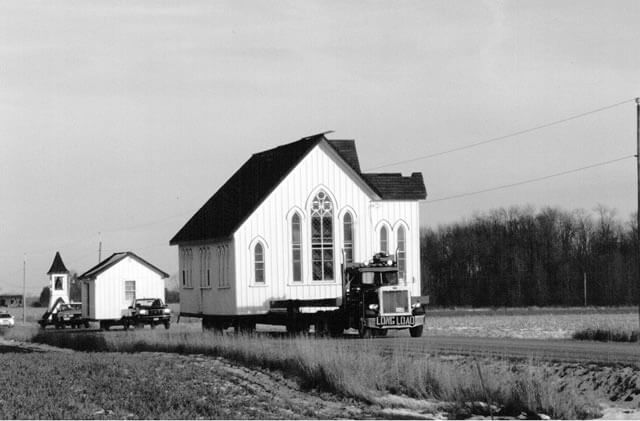Church disassembled into three parts and each part is bring transported on a truck.