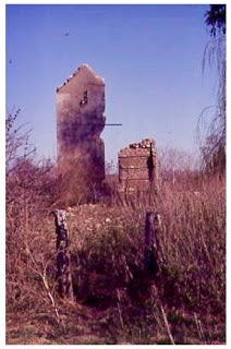 Neglected ruins of farmhouse in field with fence in front