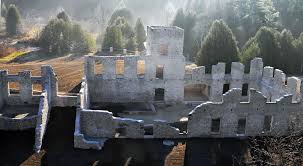 Ruined stone walls of a mill, roofless foundation and degraded walls with forest in background