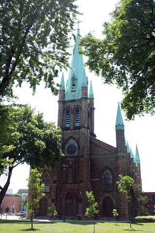 A brown brick church with copper oxide roof.