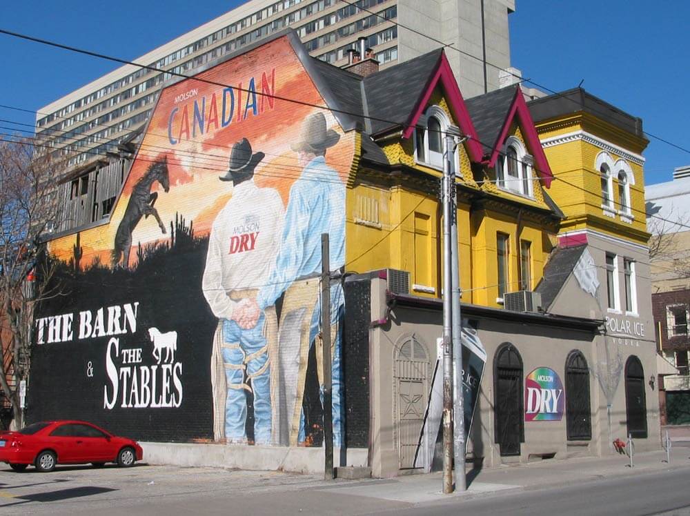 A designate heritage building with a colourful facade and mural painted on the side at Church and Grandby streets in 2010, Toronto