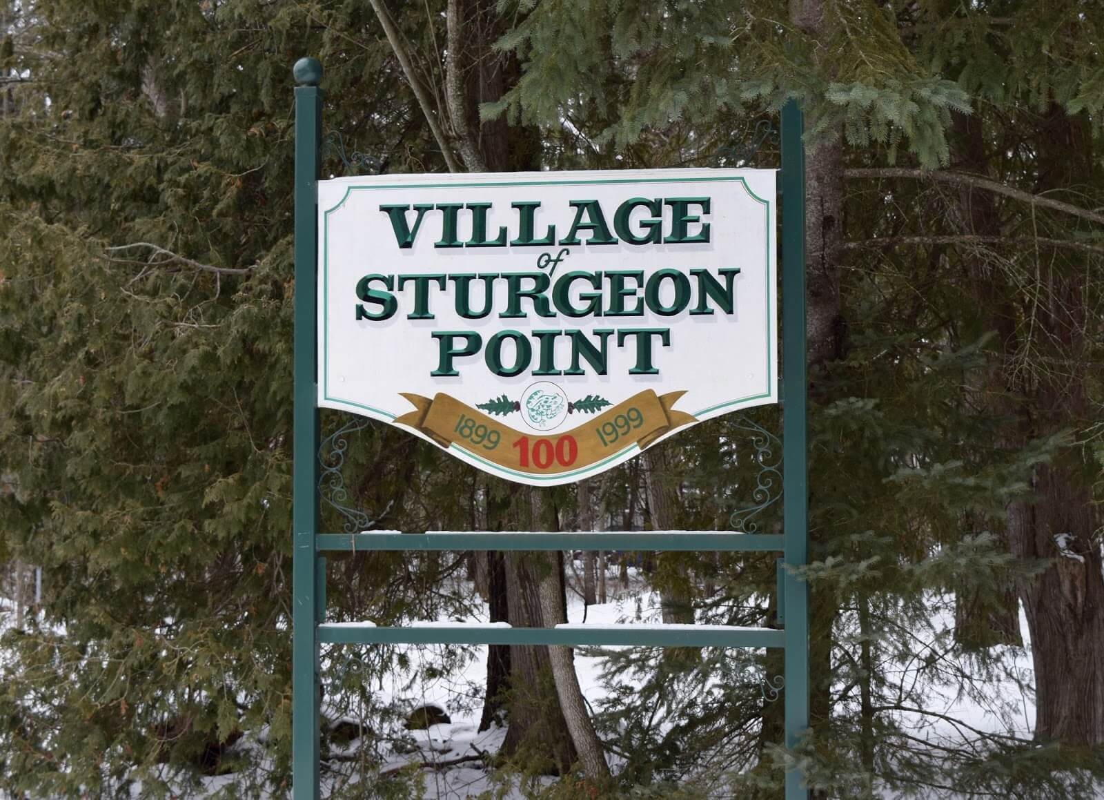 A wooden sign outside in the winter reading "Village of Sturgeon Point"