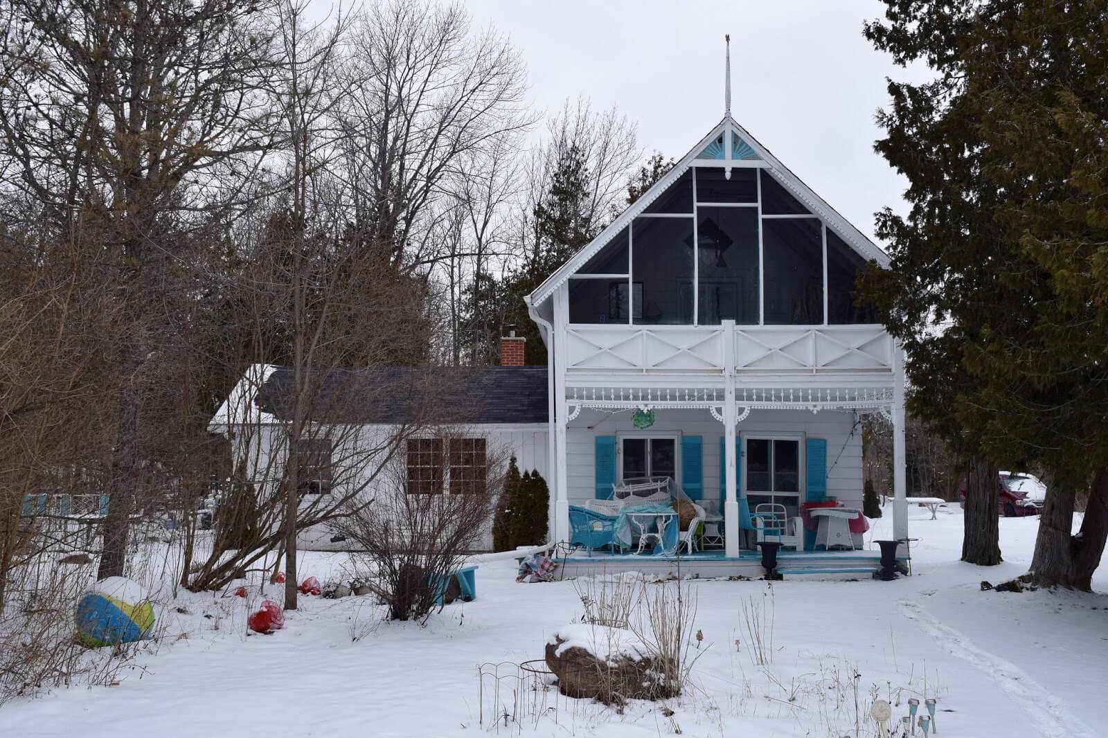 A medium sized cottage in the winter time with Ontario resort Architecture surrounded by snow