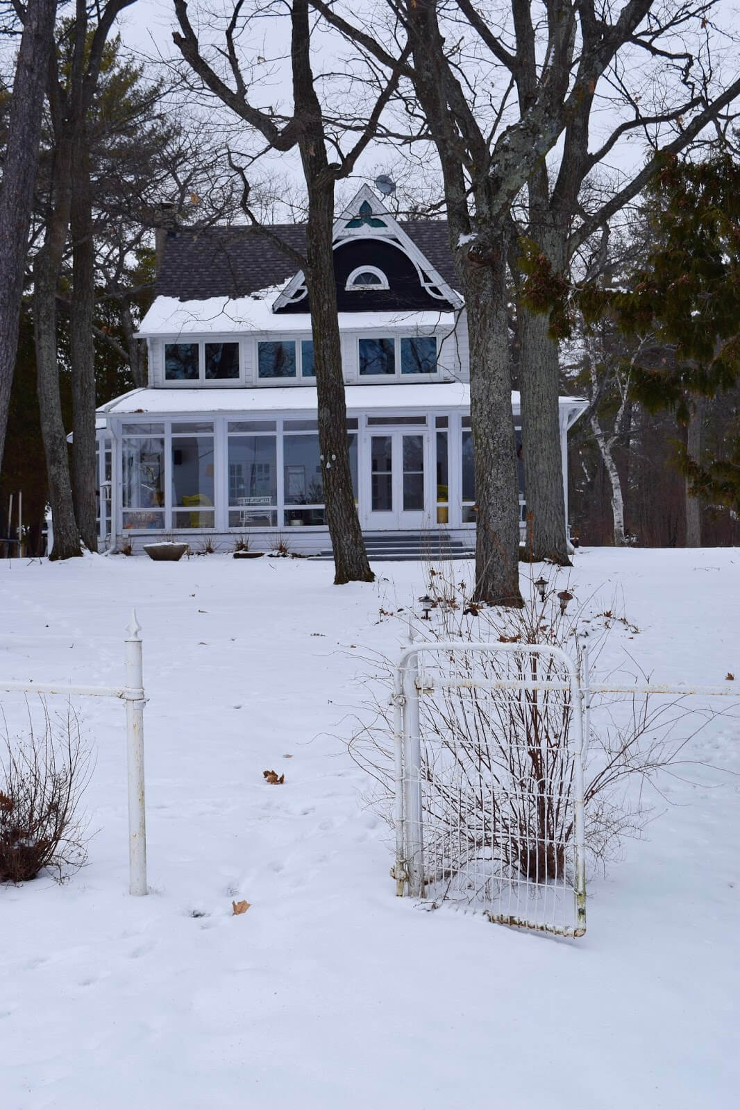 A victorian era cottage on Lake Avenue in Sturegeon Point, in the winter with a metal fence out front