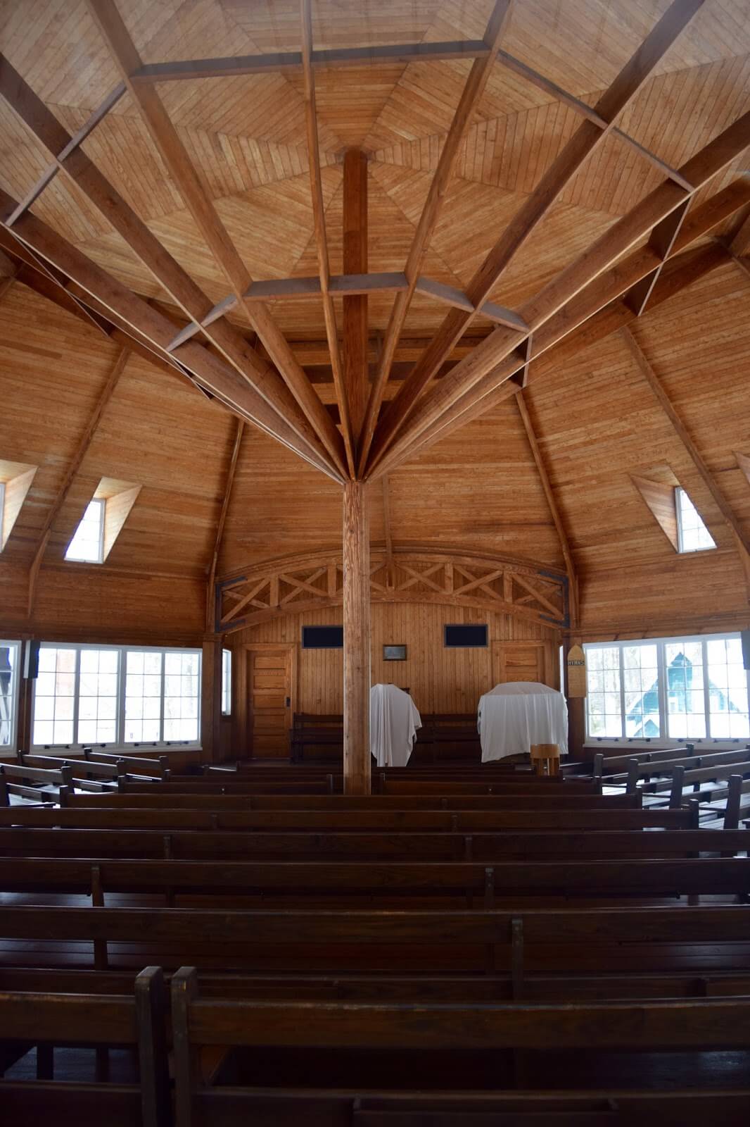 The wooden interior of the octagonal church in the sould of Sturgeon Point with a singular pillar in the centre
