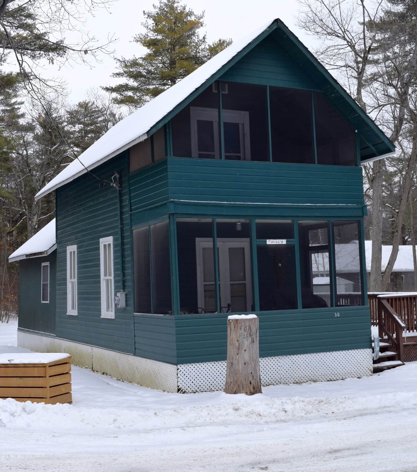 A medium sized cottage in the winter time with Ontario resort Architecture surrounded by snow