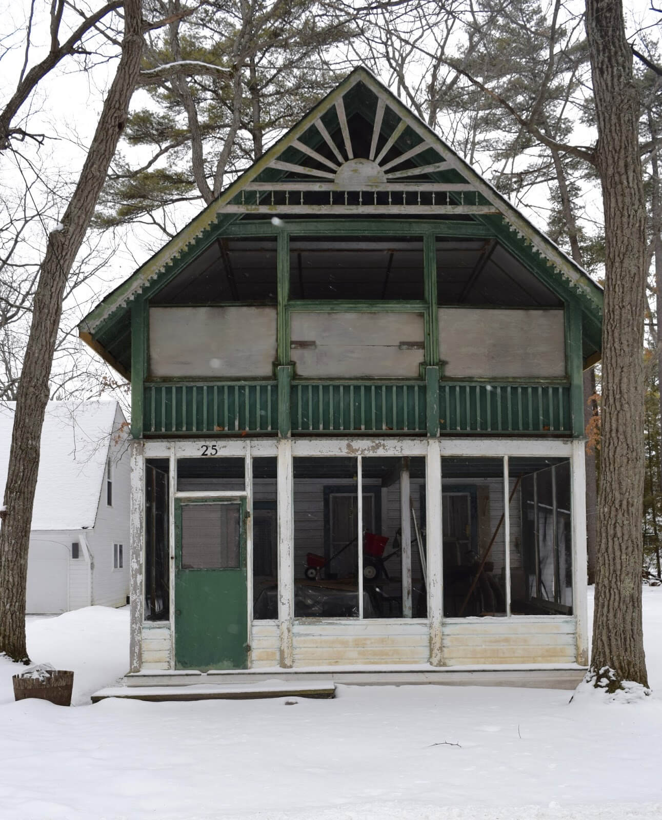 A front view of a medium sized cottage in the winter time with Ontario resort Architecture surrounded by snow