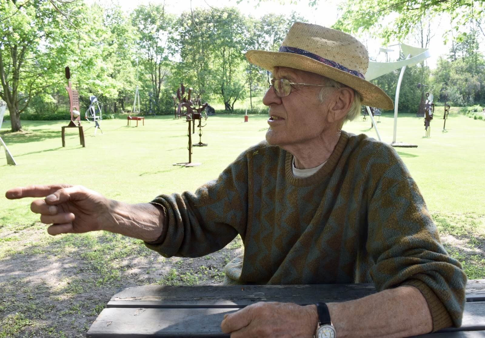 A man, Andy Drenters sitting at a picnic table pointing, behing the Rockwood Academy today