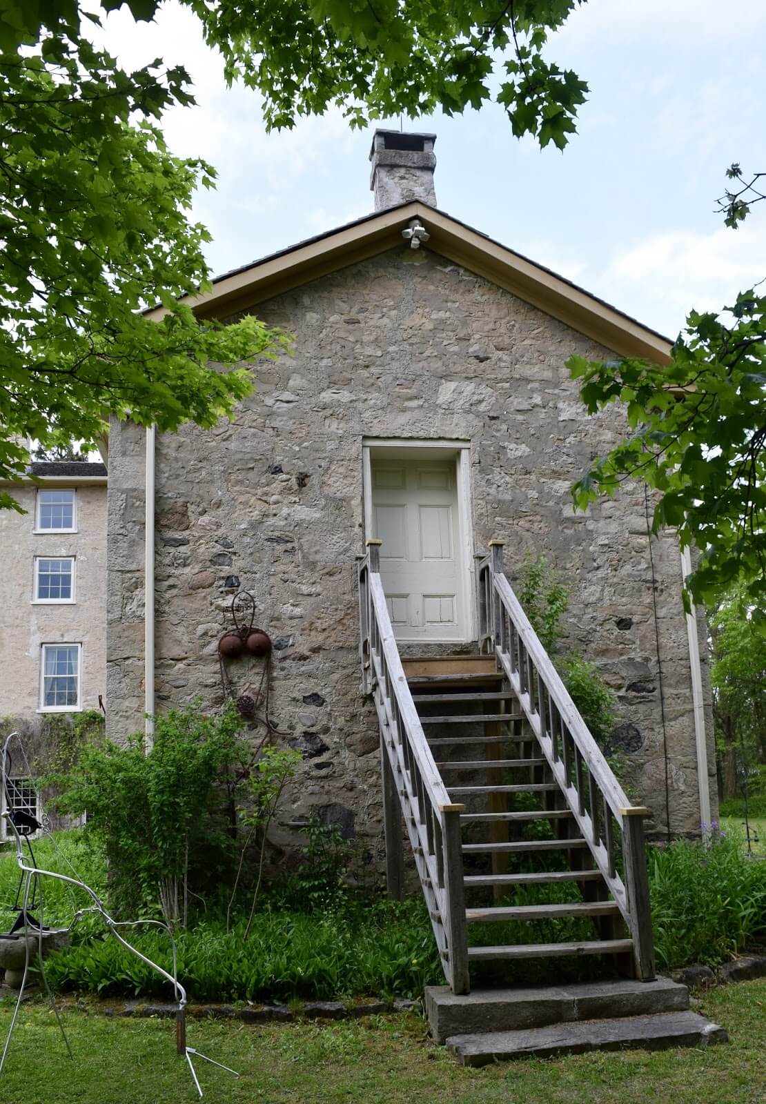 A rear perspective of the gynasium wing at Rockwod Academy, a historic stone building with staircase leading up to a door