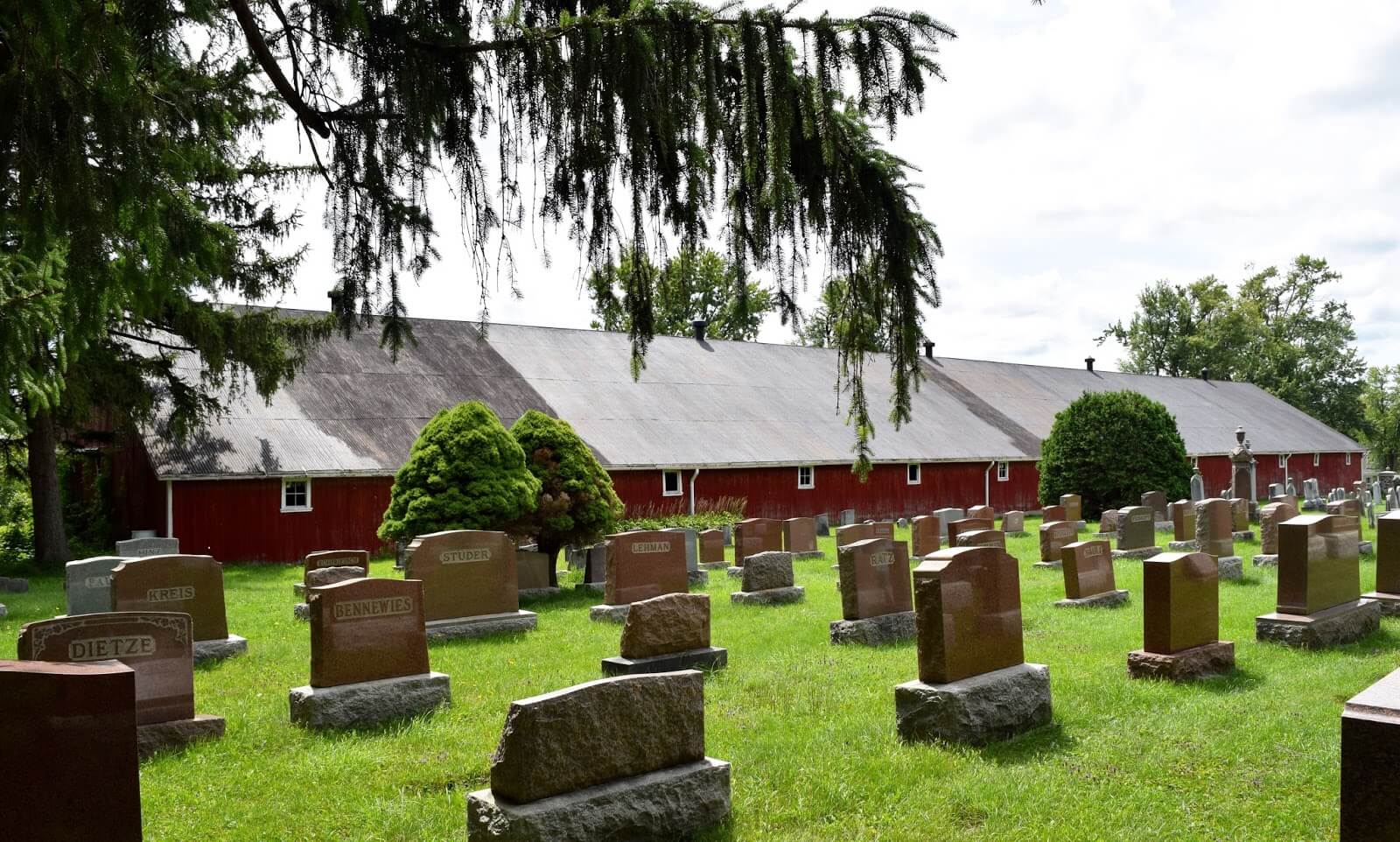 An old, red buggy barn at a cemetery.