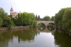 A landscape image showing stratford, a bridge over water and buildings in the background