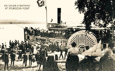 A historic black and white photot of the Esturian Steamship at Sturgeon Point surrounded by people