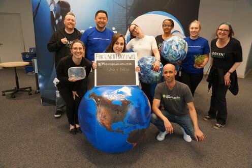 Intuit Green team employees posing for a group photo holding globes.