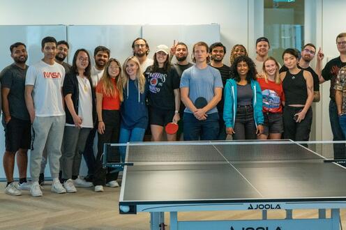 Perpetua employees and co-op students posing for a group photo in front of a ping pong table