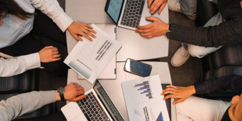 Employers sitting at a desk with laptops discussing financial graphs