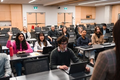 Participants raising hand in an in person employer information session