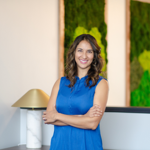 Mira Toth, clinic director and lead physiotherapist at PhysioMira smiling with arms crossed in a modern clinic setting.