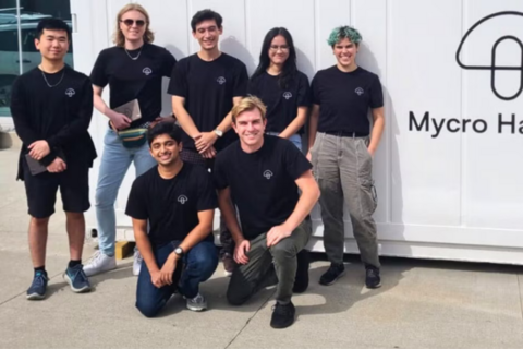 Group of Waterloo co-op students and staff smiling and standing in front of Mycro Harvest labelled shipping container