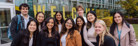 Group of Waterloo students standing in front of William M. Tatham Centre smiling