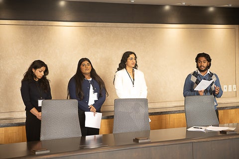 Group of students holding papers and presenting