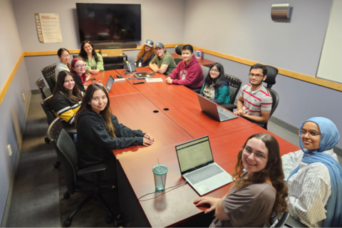 Eleven IST co-op students sitting around a large boardroom table