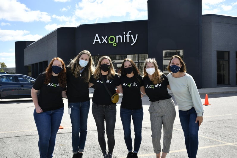 Axonify employees wearing company t-shirts posing infront of Axonify building