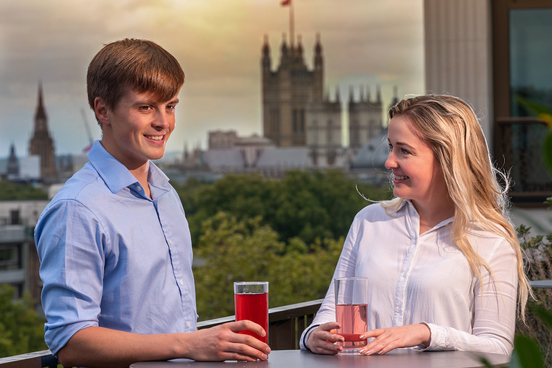 Two Capula Investment co-op students enjoying a drink outside with a parliament building behind them in the distance